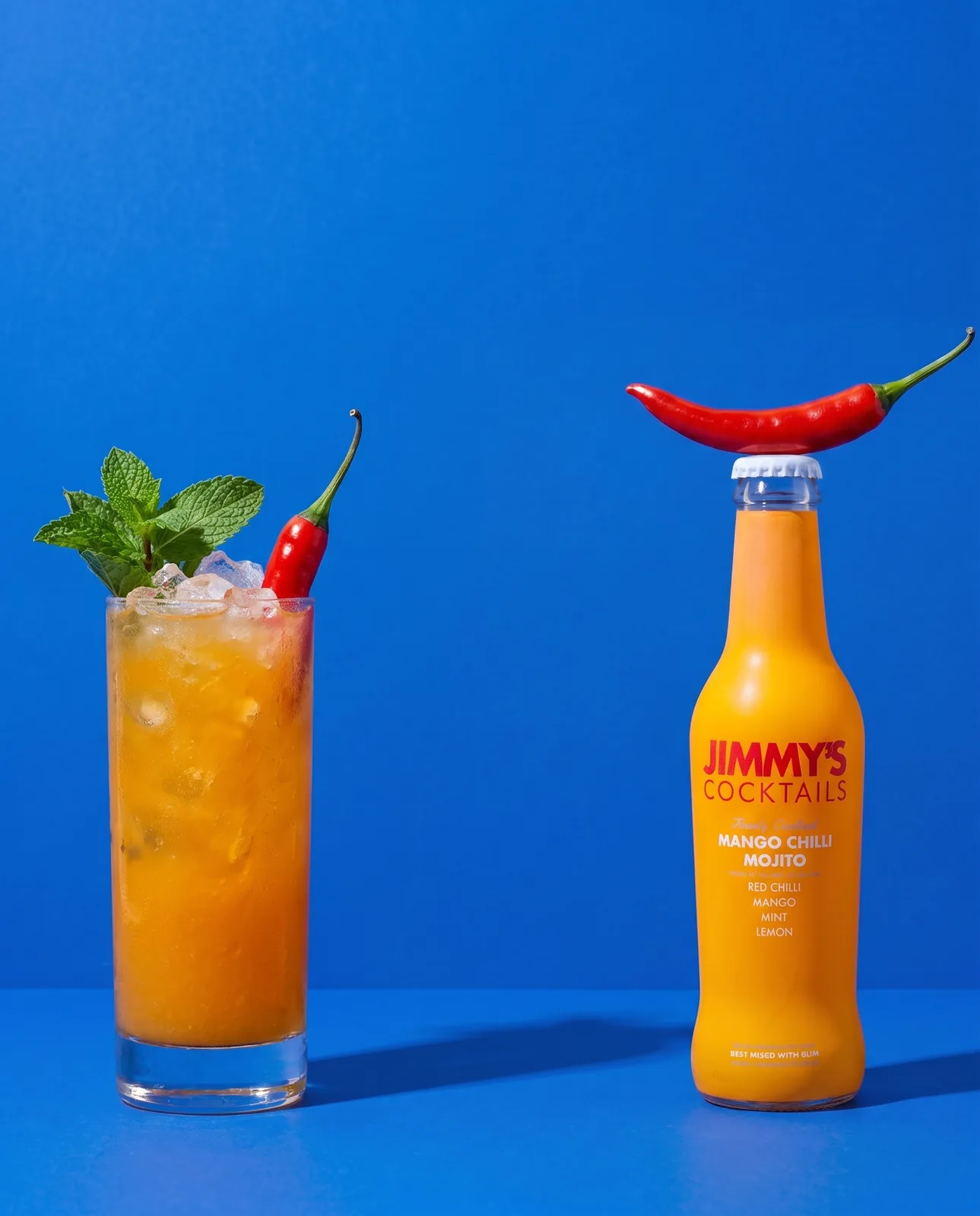 Jimmy's Cocktails bottle and a full highball glass on cobalt