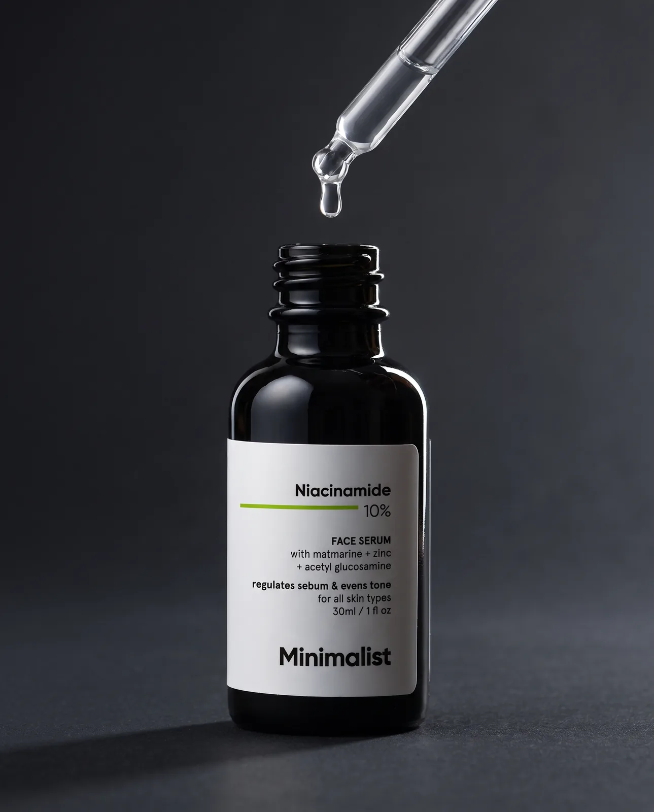 Minimalist niacinamide serum with dropper on dark